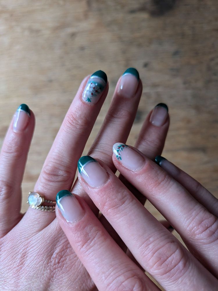 Close-up of glossy green French manicure with painted accent nail at T Nails & Spa, Seattle